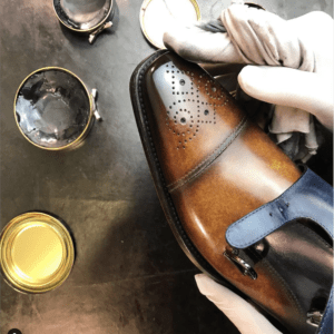 Hand met poetsdoek die de neus van een schoen opwrijft.