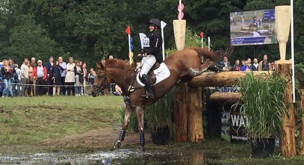 Ruiter en paard tijdens een afsprong het water in.