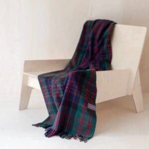 Mooie omslagdoek of kniedeken in Macdonald tartan liggend over een stoel