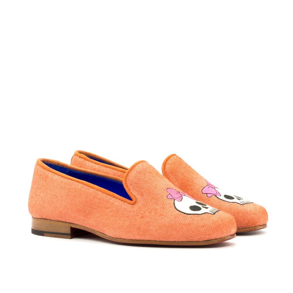 Oranje linnen slipper met een doodshoofd met roze strikje op het hoofd geborduurd.