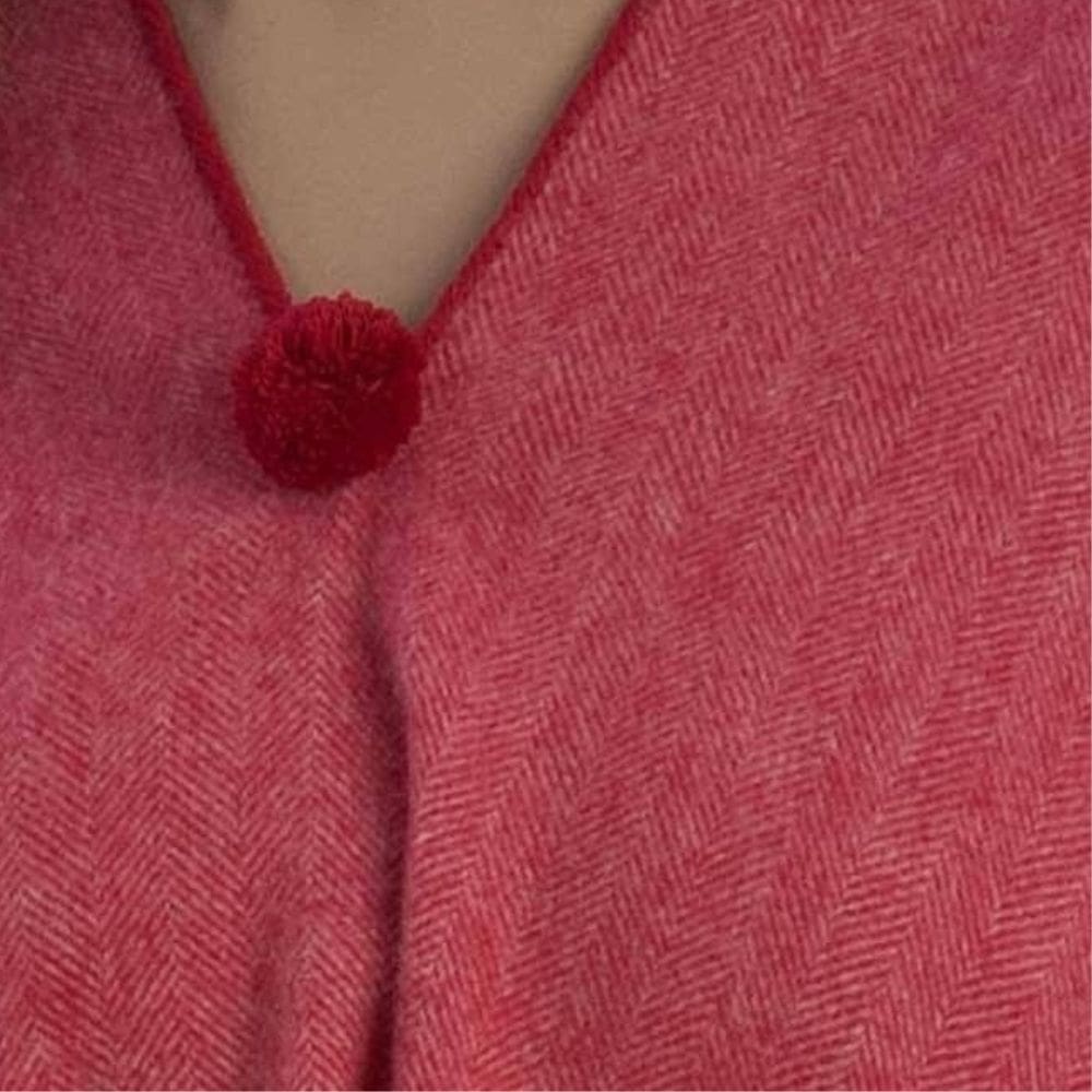 Detail van de halslijn van een rode poncho met pompom