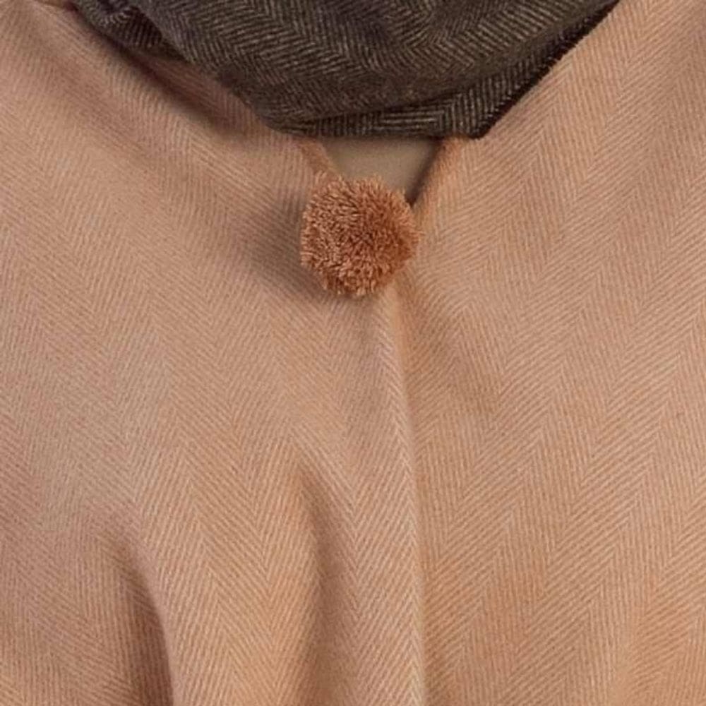 Detail halslijn van camel poncho met pompom