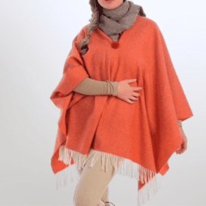 Model met een oranje lamswollen merino poncho met franjes