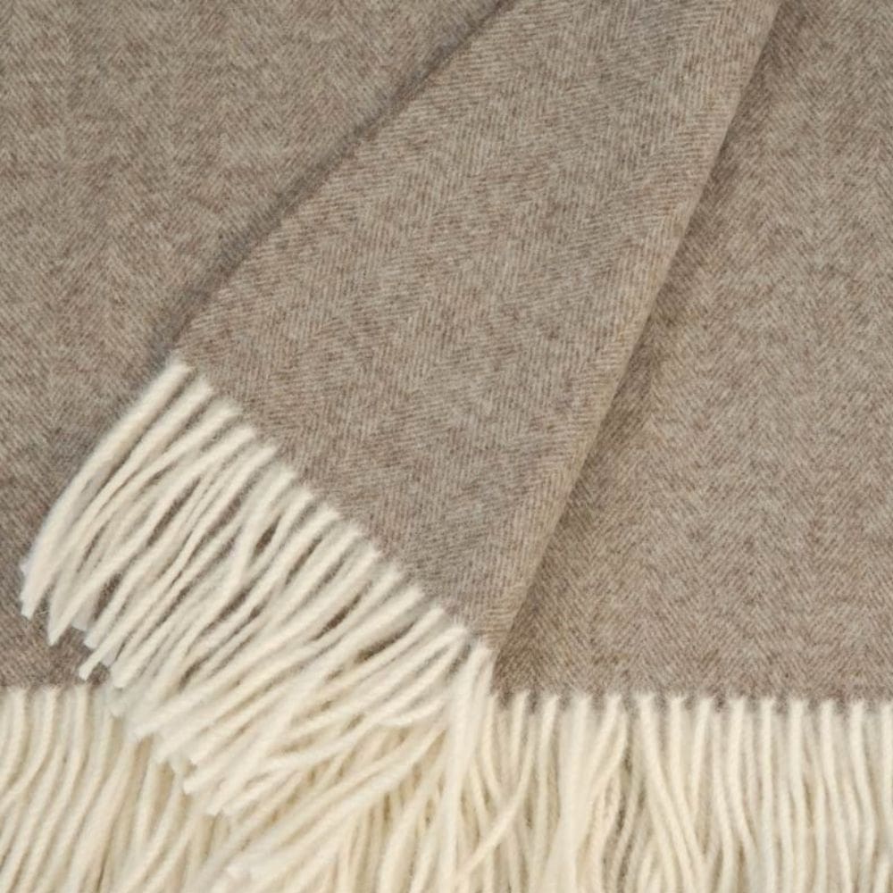 Detail van de visgraat en franjes van een taupe kleurige omslagdoek.